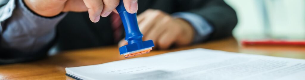 Businessman stamping with approved stamp on document at meeting.